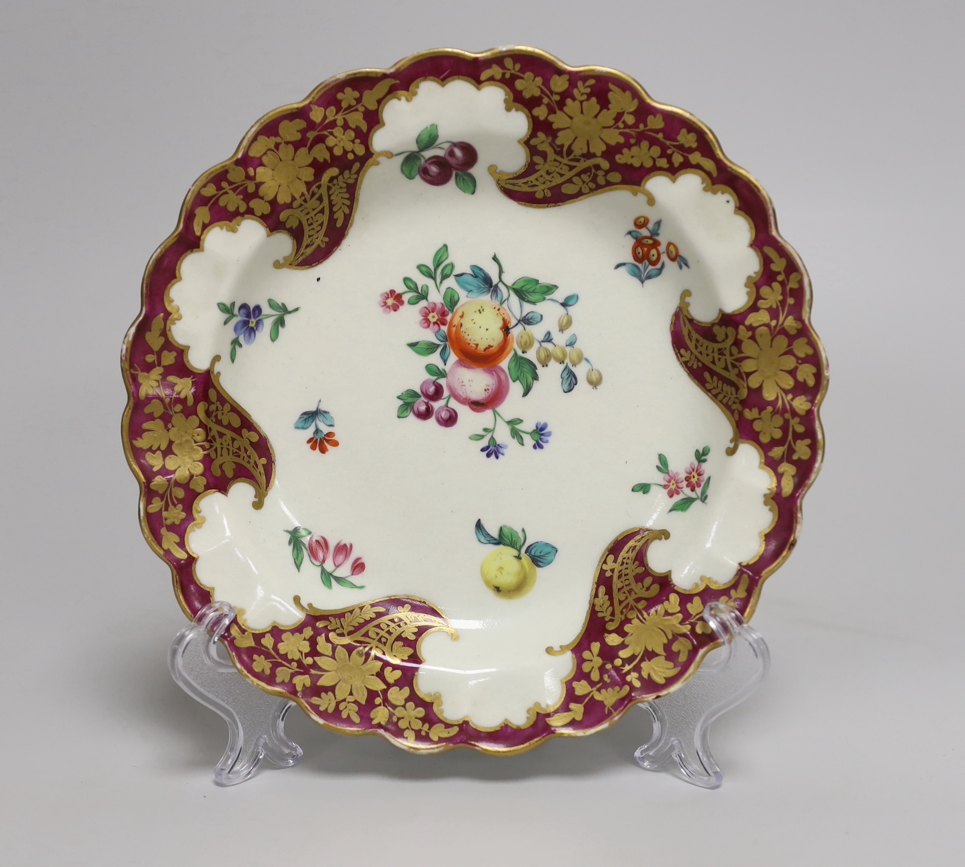 A Worcester small plate painted with fruit and flowers under a crimson and floral gilt border, 17.5cm diameter